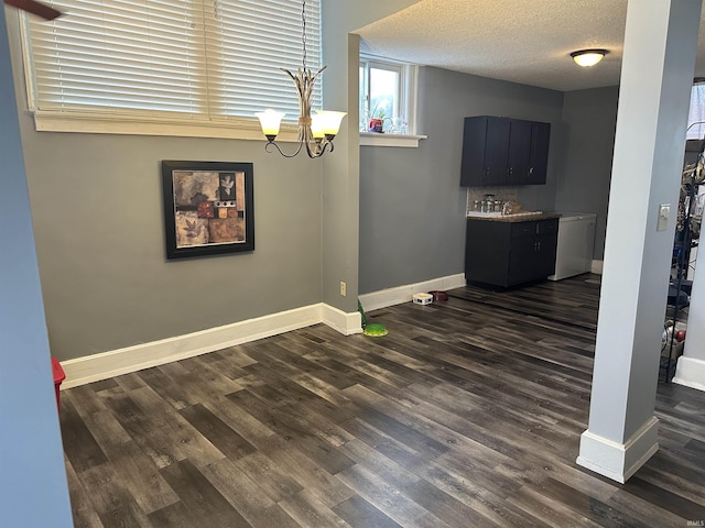 unfurnished dining area featuring dark wood-type flooring, a chandelier, and a textured ceiling