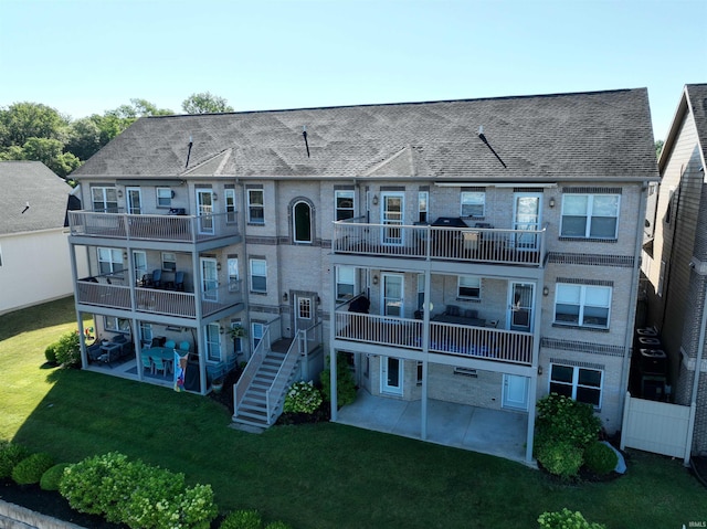 back of property with a balcony, a lawn, and a patio area