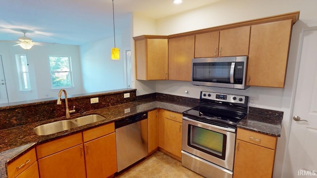 kitchen with stainless steel appliances, dark stone countertops, sink, and pendant lighting