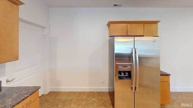 kitchen with dark stone countertops and stainless steel fridge