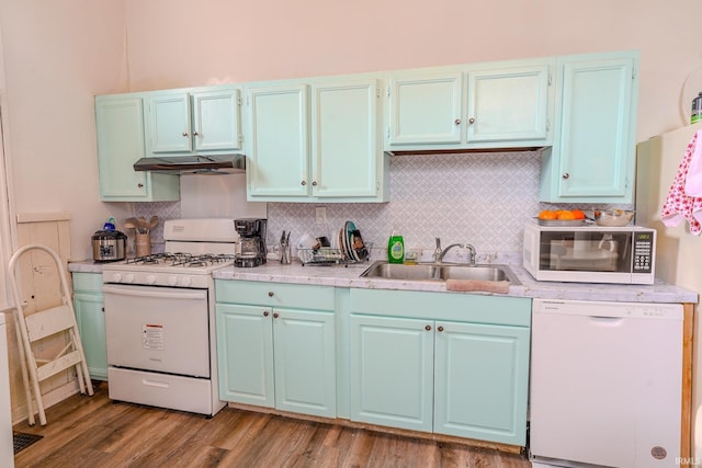 kitchen with tasteful backsplash, sink, white appliances, and hardwood / wood-style flooring