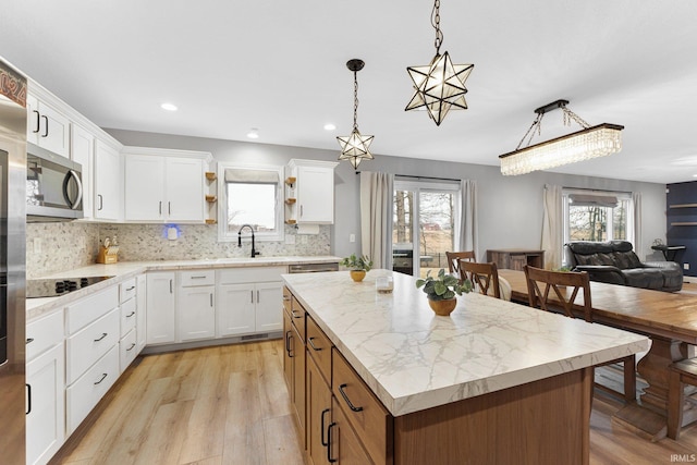 kitchen featuring sink, a center island, pendant lighting, black electric stovetop, and white cabinets