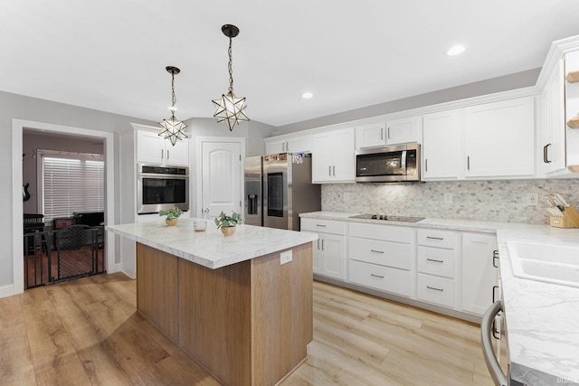 kitchen featuring appliances with stainless steel finishes, backsplash, white cabinets, a kitchen island, and decorative light fixtures