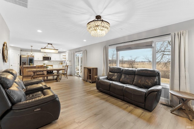 living room with a notable chandelier and light hardwood / wood-style floors