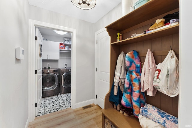 laundry room featuring cabinets, light wood-type flooring, and independent washer and dryer