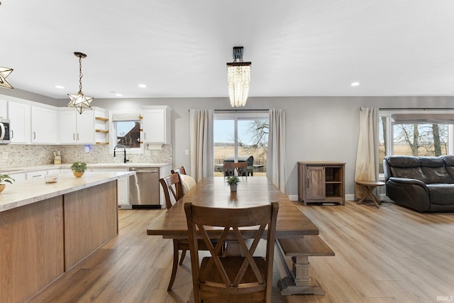 dining room with sink, a healthy amount of sunlight, and light wood-type flooring