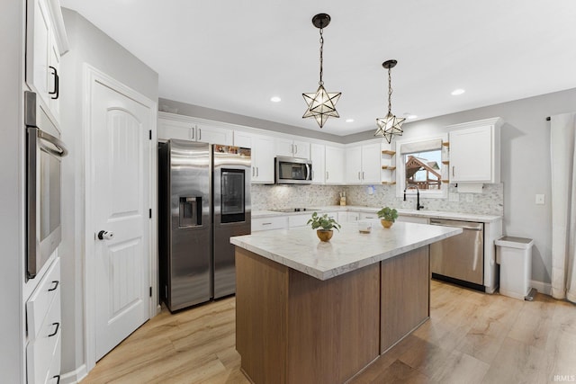 kitchen with a kitchen island, decorative light fixtures, sink, white cabinets, and stainless steel appliances