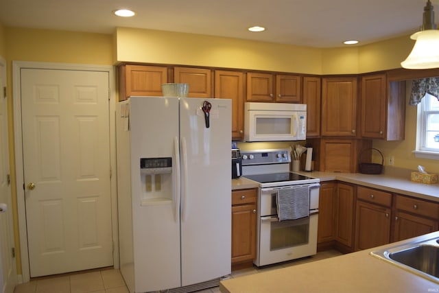 kitchen featuring white appliances, decorative light fixtures, and light tile patterned floors