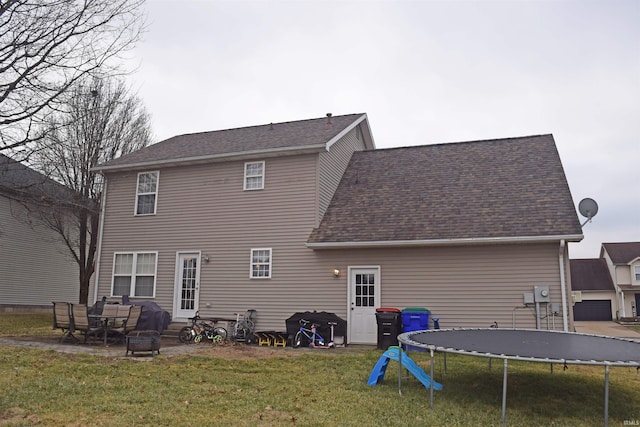 back of house featuring a yard, a patio area, and a trampoline