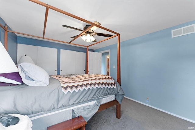 carpeted bedroom with ceiling fan and two closets