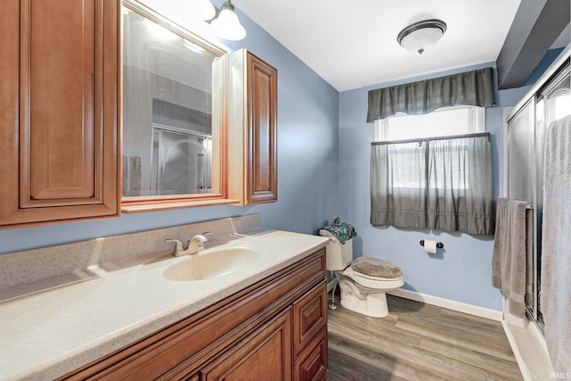 bathroom featuring vanity, hardwood / wood-style floors, a shower with shower door, and toilet