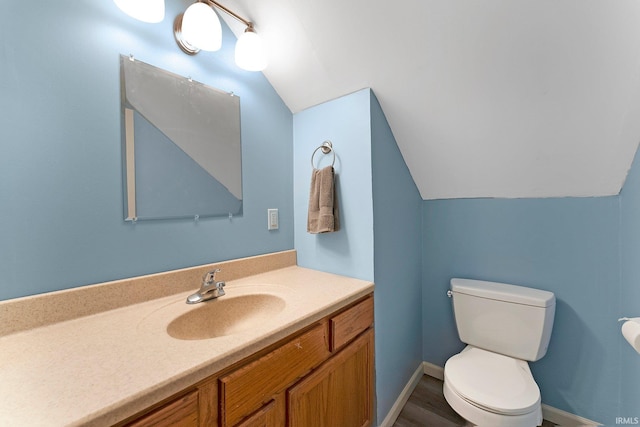 bathroom with lofted ceiling, toilet, and vanity