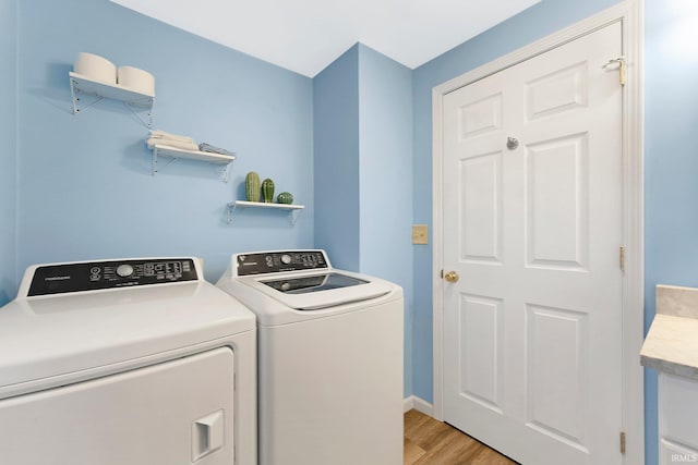 clothes washing area featuring washing machine and clothes dryer and light hardwood / wood-style floors