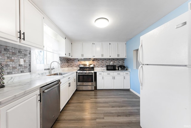 kitchen with dark hardwood / wood-style floors, sink, white cabinets, stainless steel appliances, and light stone countertops