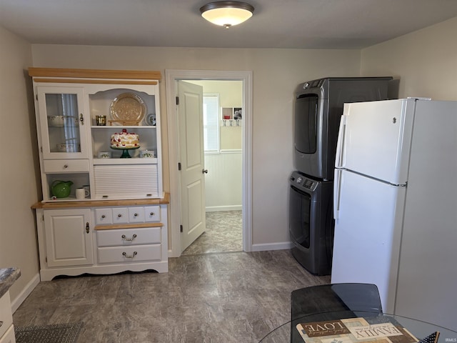 kitchen featuring stacked washer / drying machine, white cabinets, and white fridge