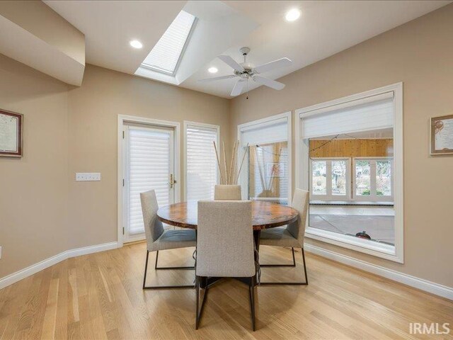 dining area with ceiling fan, light wood-type flooring, and a skylight