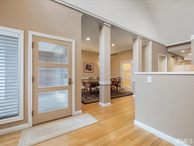 entryway with crown molding, decorative columns, and light hardwood / wood-style floors