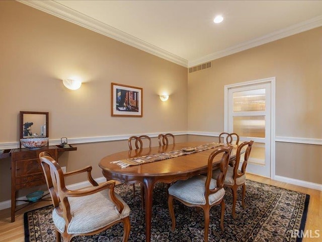 dining space featuring crown molding and light hardwood / wood-style flooring