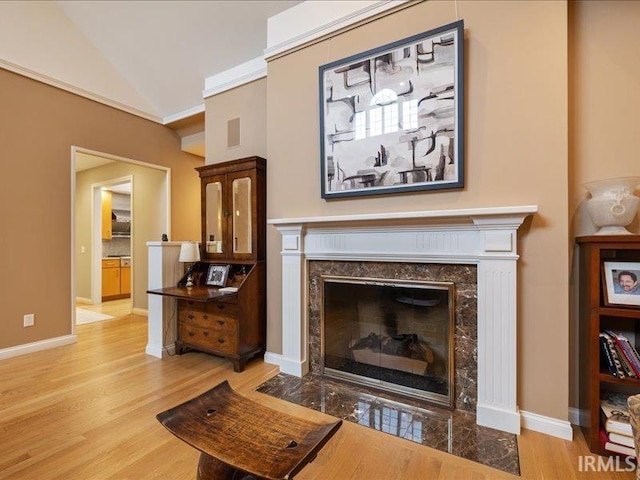 interior space featuring lofted ceiling, a high end fireplace, and light hardwood / wood-style floors