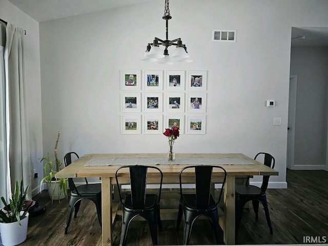 dining area featuring dark wood-type flooring and an inviting chandelier