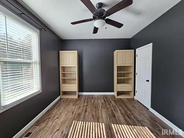 unfurnished bedroom featuring ceiling fan and dark hardwood / wood-style flooring