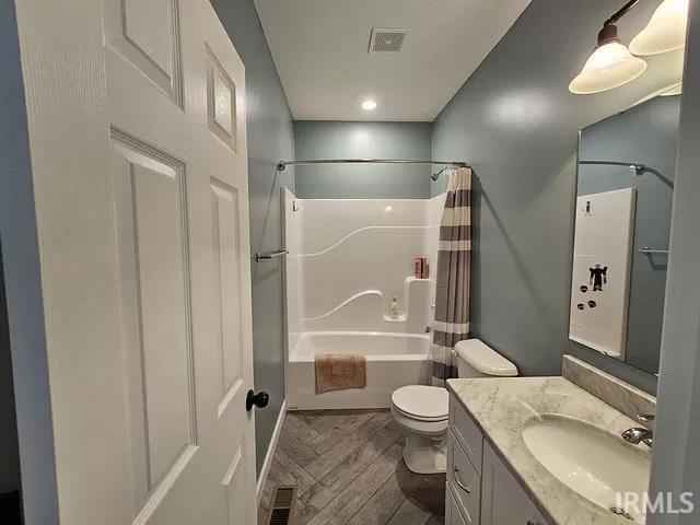 full bathroom with vanity, parquet floors, shower / tub combo, and toilet