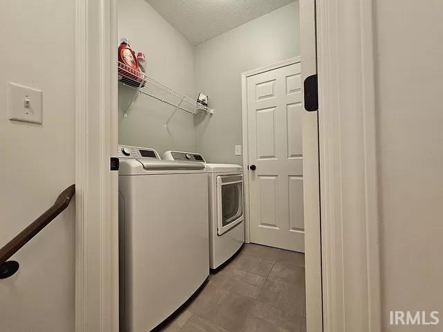 clothes washing area featuring washer and clothes dryer and a textured ceiling