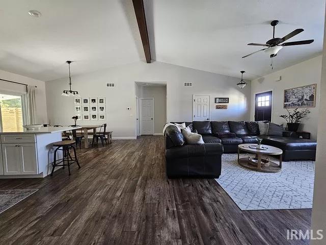 living room with ceiling fan, dark hardwood / wood-style flooring, and lofted ceiling with beams