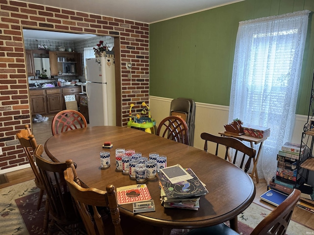 dining area featuring hardwood / wood-style floors and brick wall