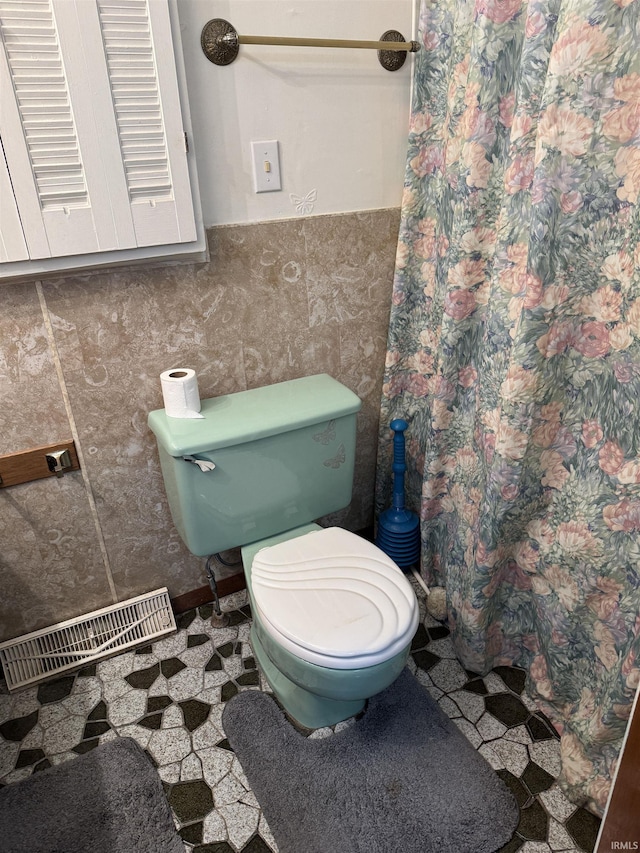 bathroom featuring tile walls and toilet