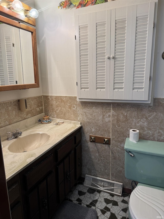 bathroom featuring vanity, tile walls, and toilet