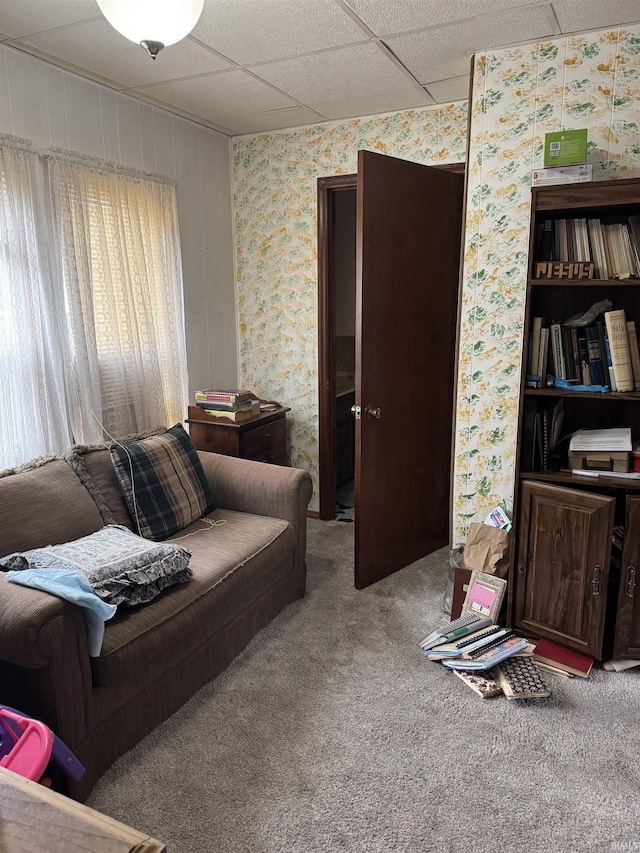 carpeted living room featuring a drop ceiling