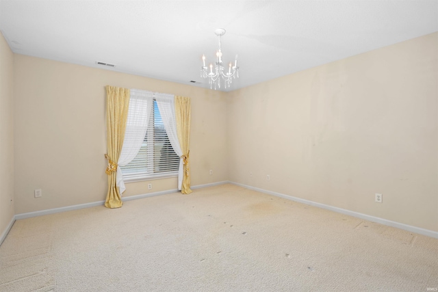 carpeted spare room with a chandelier