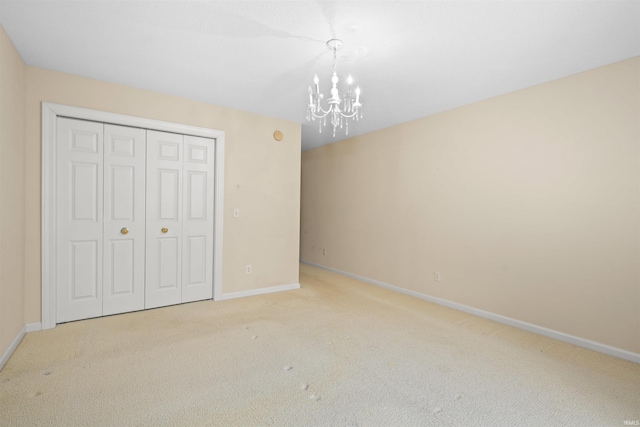 unfurnished bedroom with light carpet, an inviting chandelier, and a closet