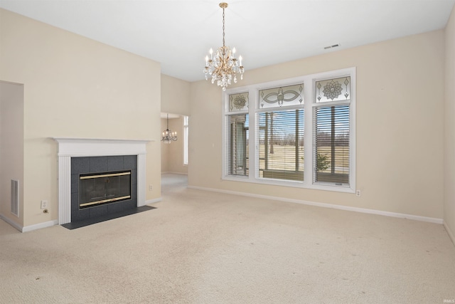 unfurnished living room with a tiled fireplace, a notable chandelier, and light colored carpet