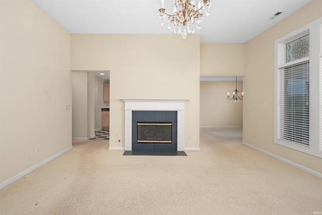 unfurnished living room with an inviting chandelier, a tiled fireplace, and light carpet