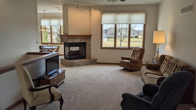 carpeted living room with ceiling fan, track lighting, and a brick fireplace