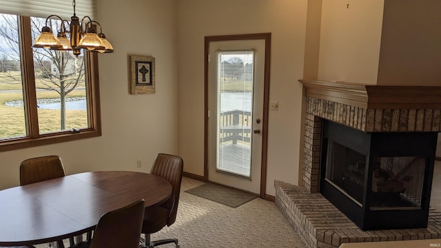 dining area with a fireplace, a chandelier, and carpet floors