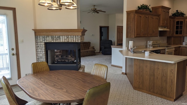 kitchen with pendant lighting, white electric range, a multi sided fireplace, light colored carpet, and kitchen peninsula