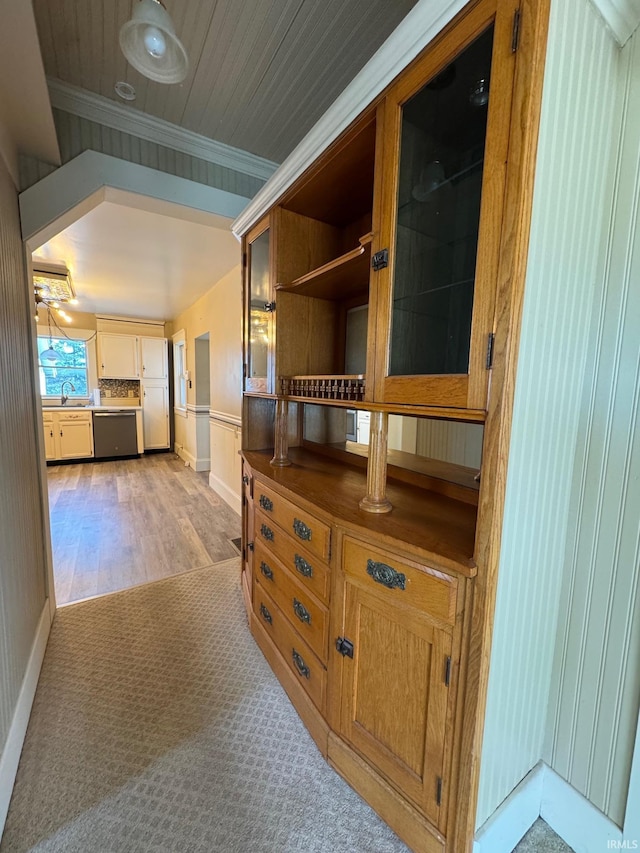 hall featuring light colored carpet, ornamental molding, and sink