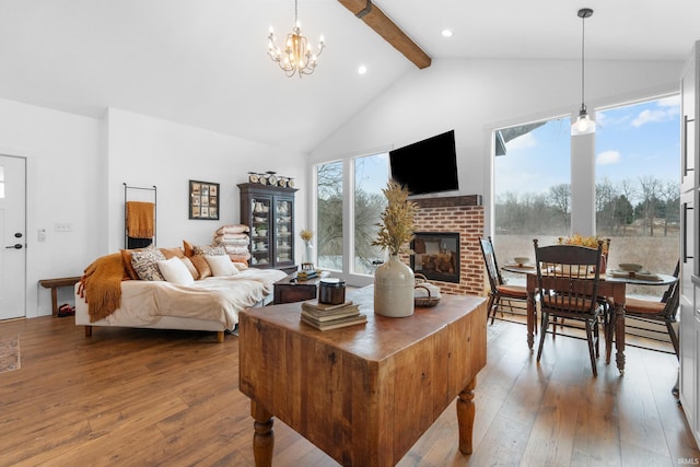 living room featuring high vaulted ceiling, hardwood / wood-style flooring, a notable chandelier, a brick fireplace, and beam ceiling