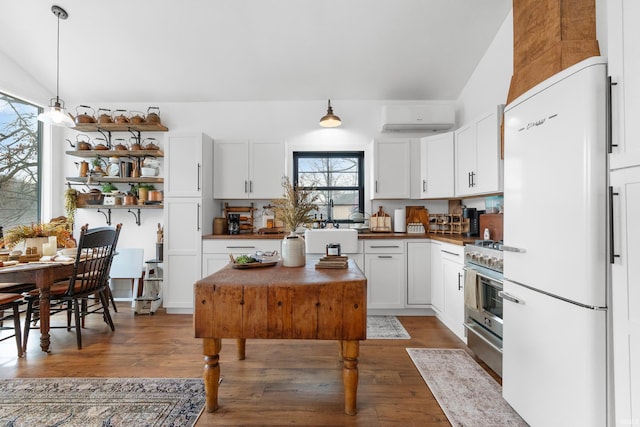 kitchen with white cabinets, white refrigerator, high end stainless steel range, dark wood-type flooring, and a wall unit AC