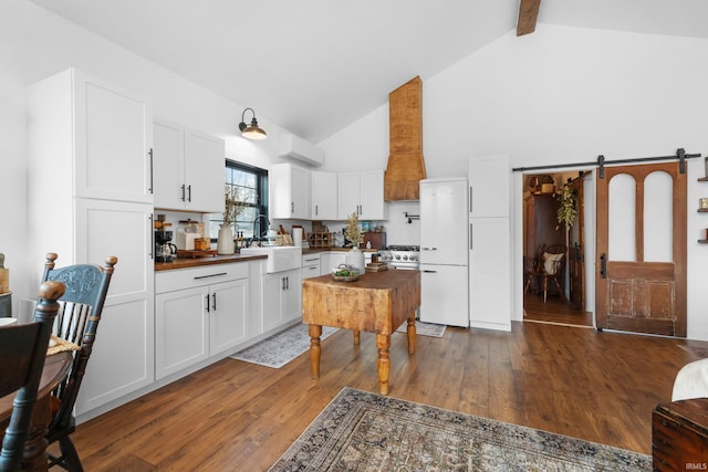 kitchen featuring sink, white cabinetry, white refrigerator, dark hardwood / wood-style floors, and a barn door