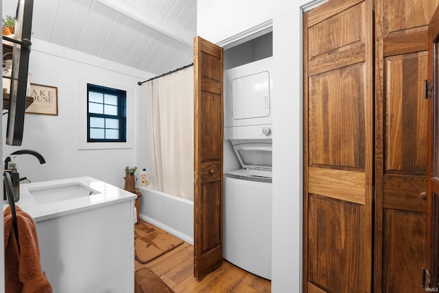 washroom featuring stacked washer / drying machine, sink, light hardwood / wood-style flooring, and wooden ceiling