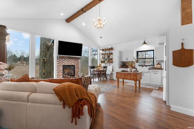 living room with beamed ceiling, an inviting chandelier, high vaulted ceiling, a brick fireplace, and hardwood / wood-style flooring