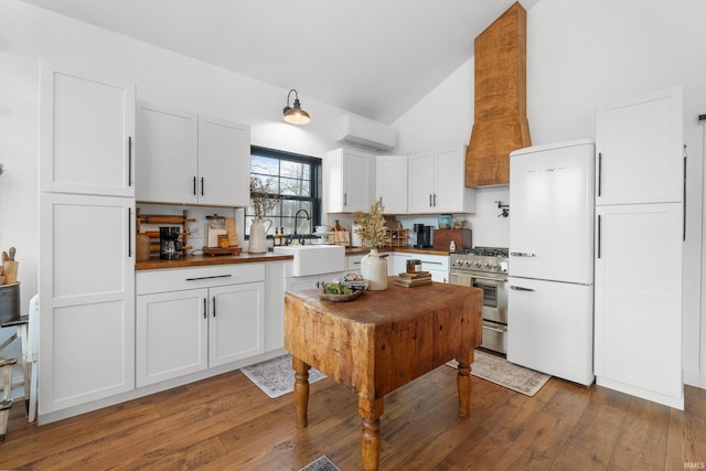 kitchen featuring sink, stainless steel stove, a wall mounted AC, white cabinets, and white fridge