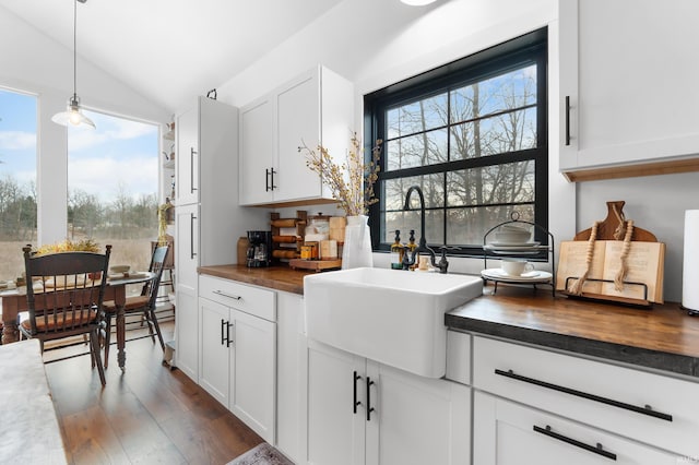 kitchen with lofted ceiling, sink, decorative light fixtures, dark hardwood / wood-style flooring, and white cabinets