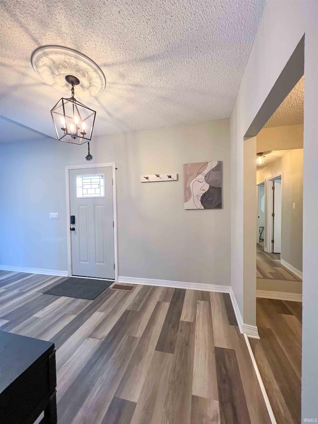 foyer entrance with a notable chandelier, wood-type flooring, and a textured ceiling