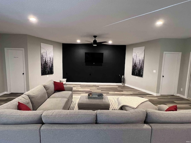 home theater room with hardwood / wood-style floors, a textured ceiling, and ceiling fan