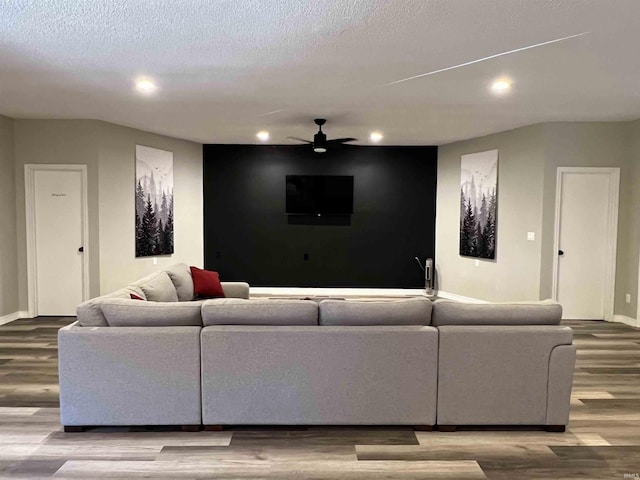 living room with hardwood / wood-style flooring, ceiling fan, and a textured ceiling